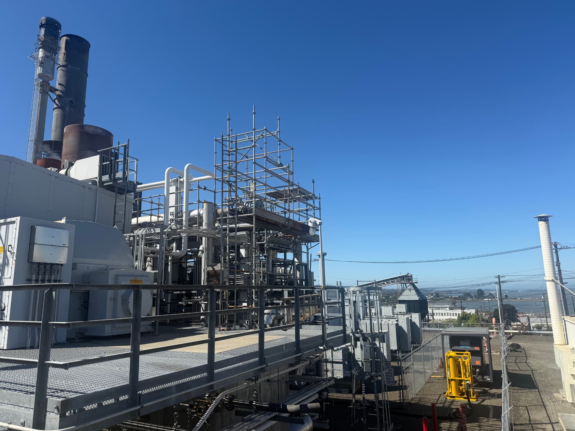 Refinery process unit with stacks and scaffolding overlooking the bay.
