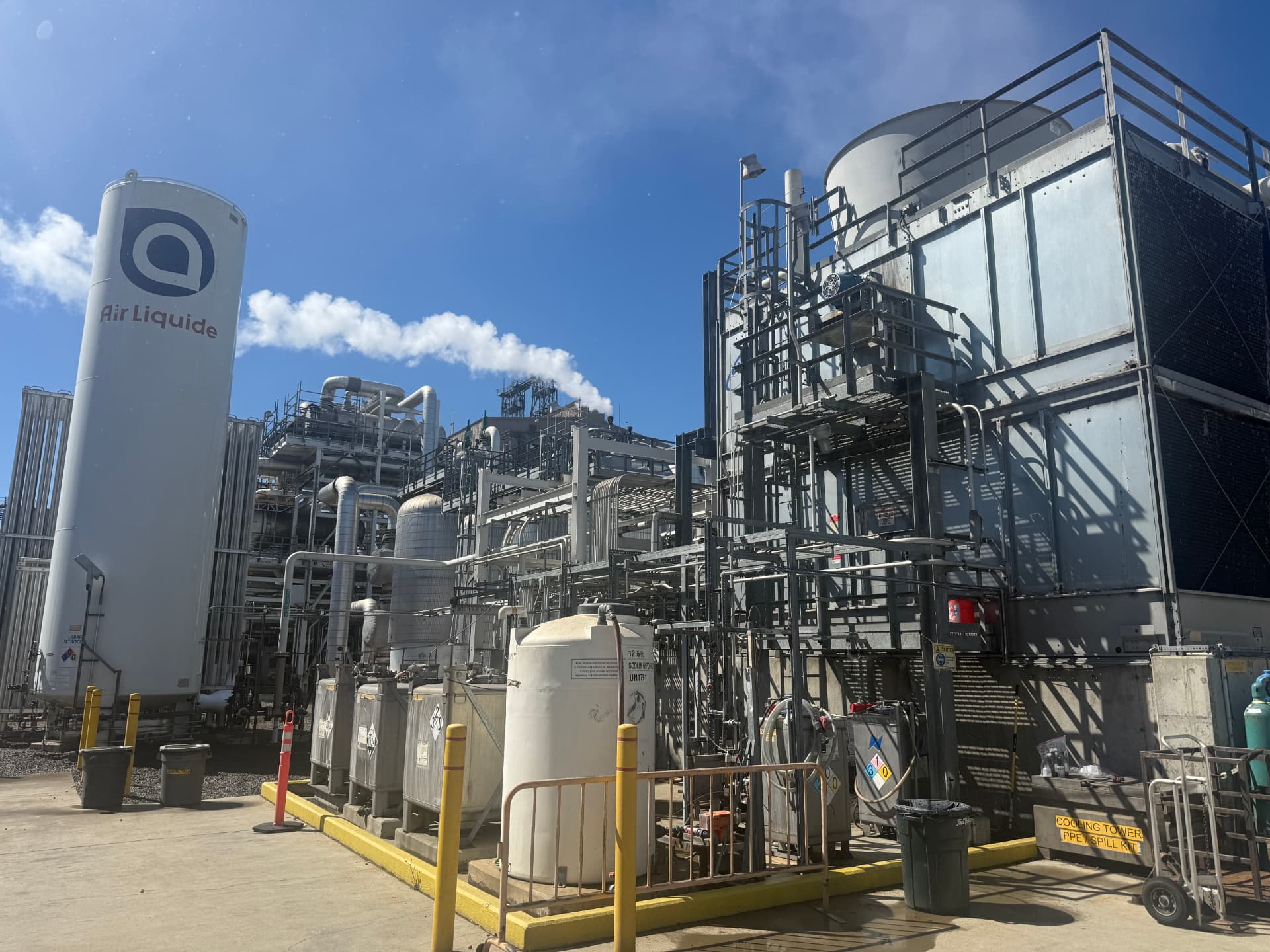 Industrial process facility with cooling tower and storage tanks.