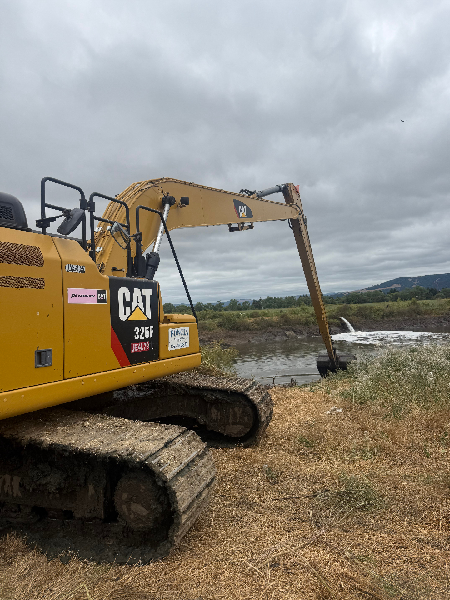 Long-reach excavator supporting discharge channel maintenance at a field site.
